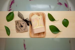 Wooden display with clock and soap bar decoratively arranged with green leaves.