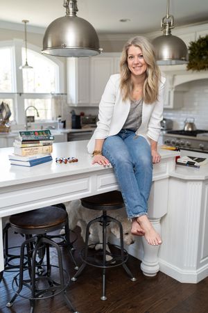 Casual lifestyle photo of person sitting on kitchen counter with books and industrial pendant lighting.