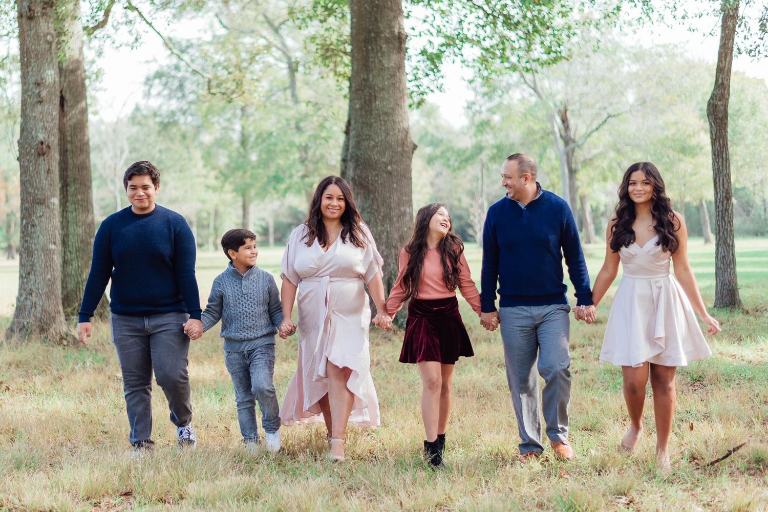 Family walking together and holding hands in park setting