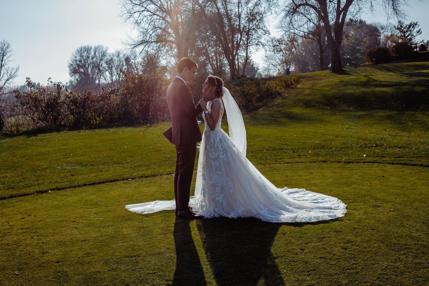 Silhouetted wedding couple standing on grassy hill during golden hour.