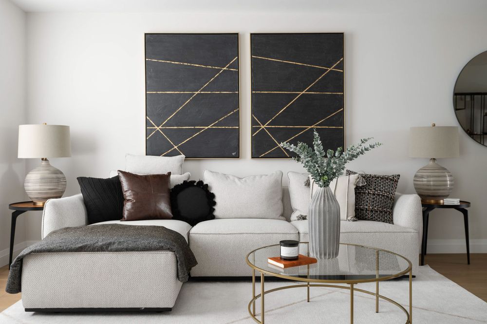 Contemporary living room with grey sectional sofa and geometric black and gold wall art.