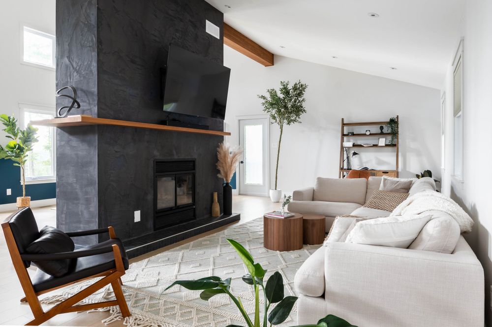 Modern living room featuring black fireplace, leather chair and white sectional with indoor plants.