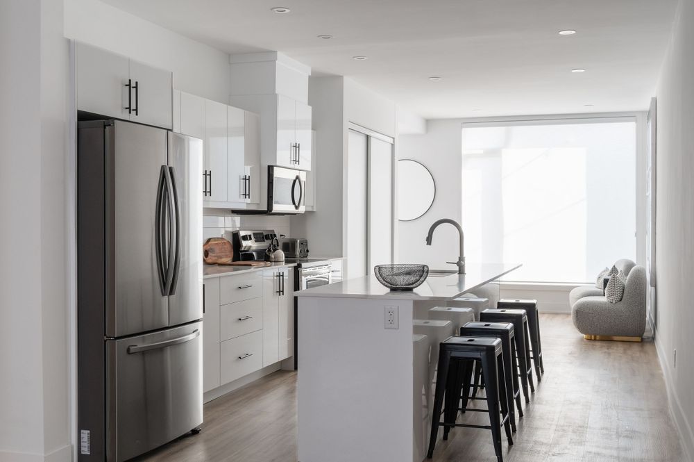 Modern white kitchen interior with stainless appliances and island seating.
