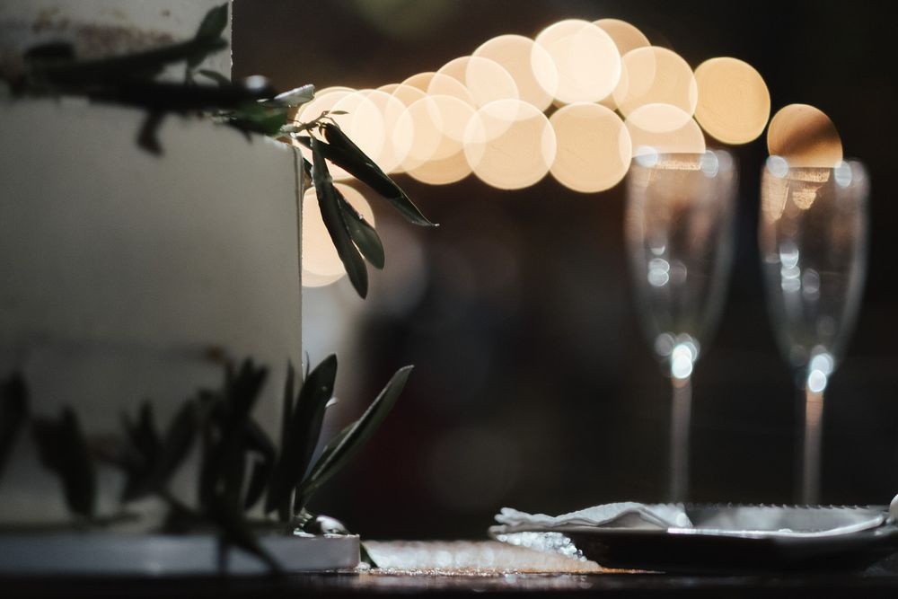 Ambiente romântico com flutes de champanhe e luzes de cordão criando um efeito bokeh.