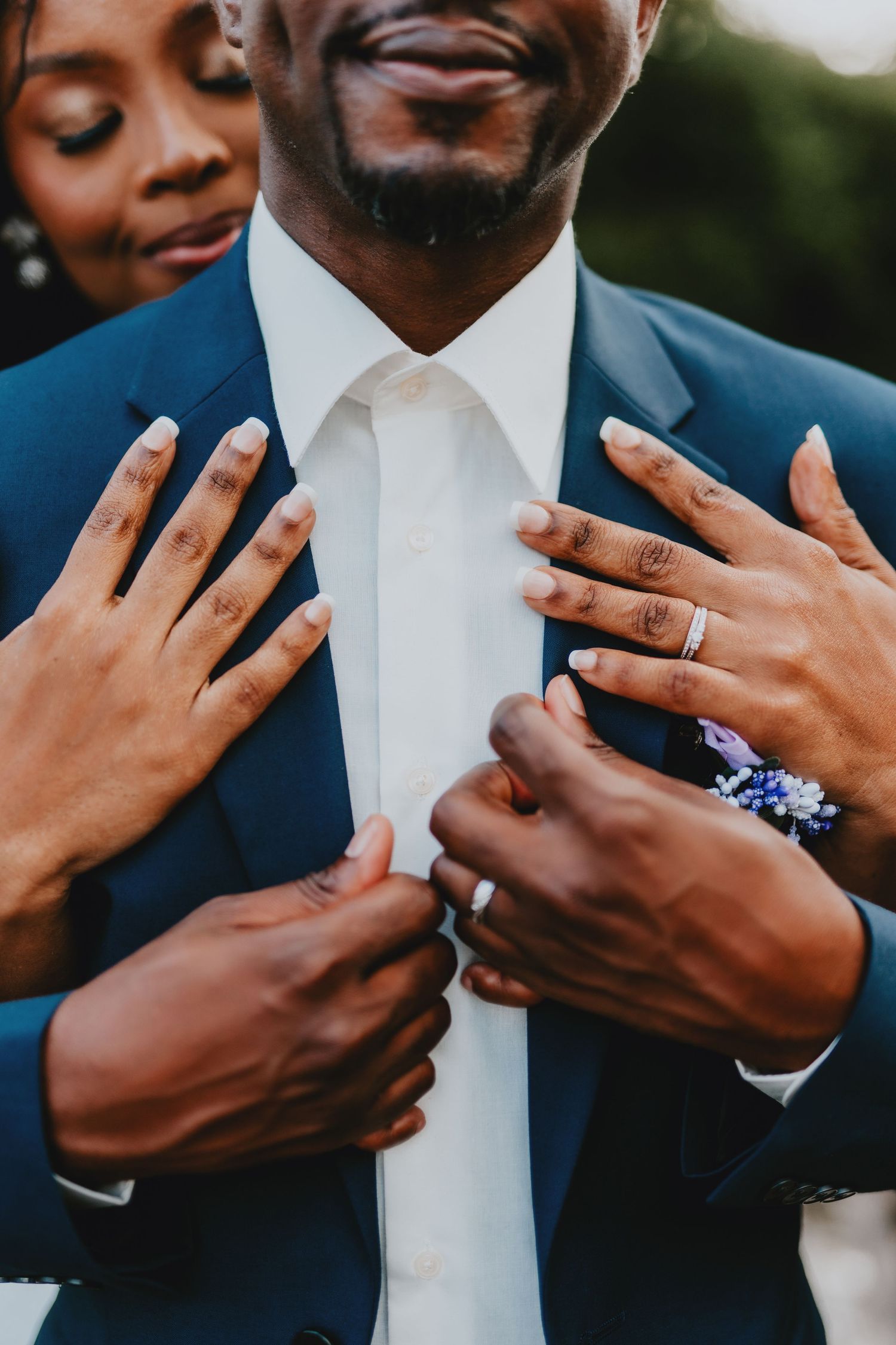 Close up of hands showing wedding rings against a navy blue suit.