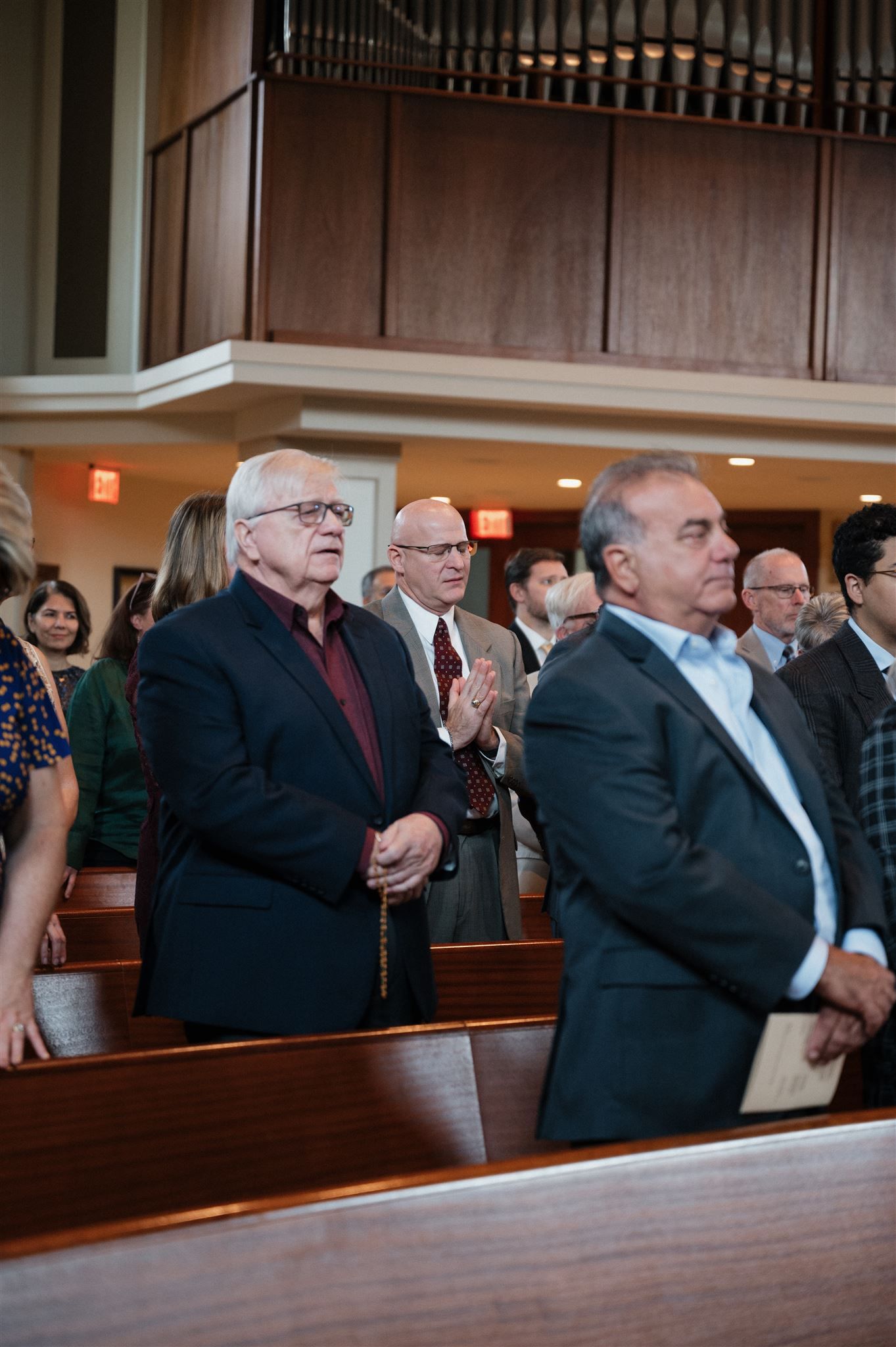 Wedding guests watching ceremony from wooden church pews in a traditional sanctuary.