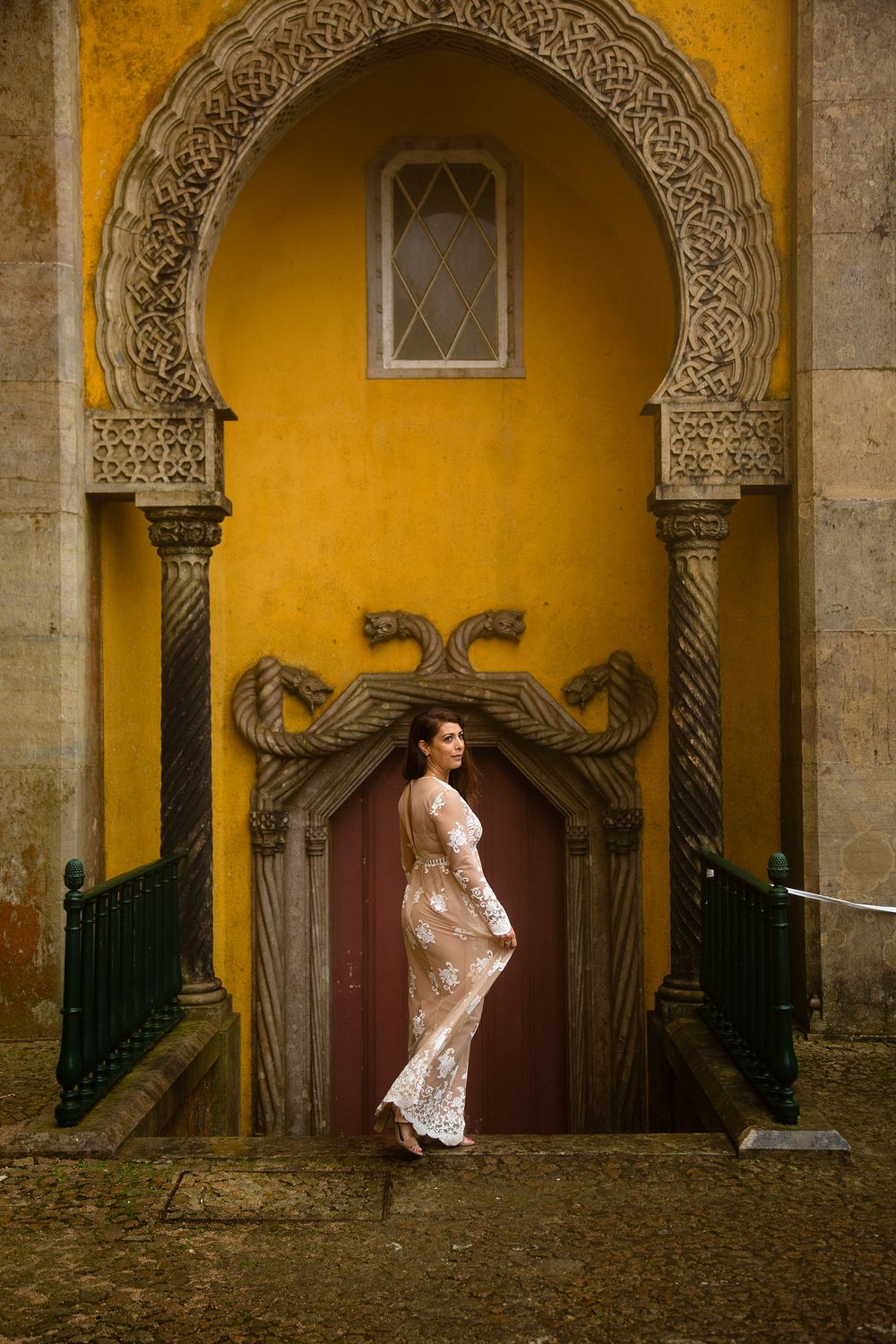 White lace dress against ornate yellow Moorish archway and decorated door.