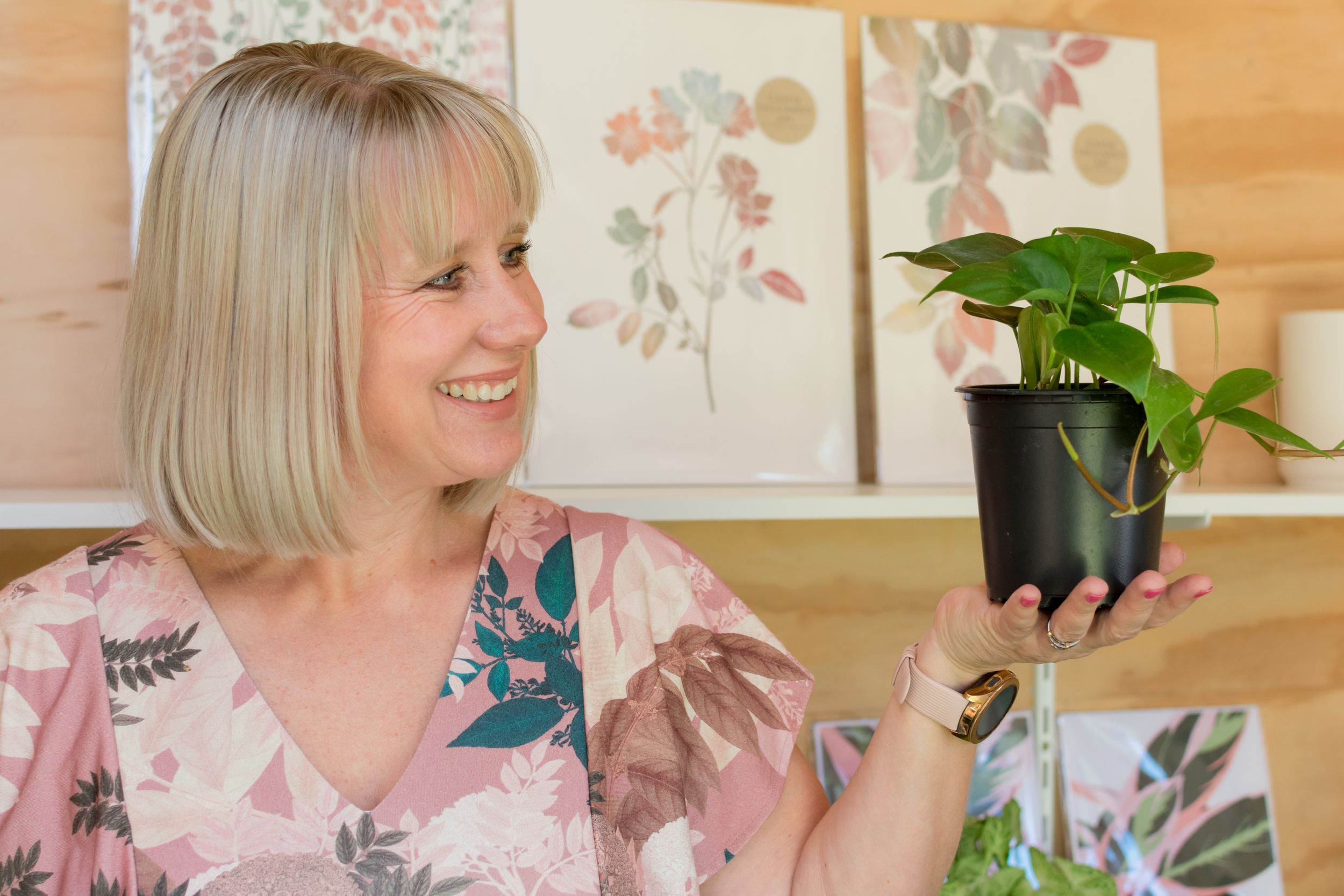 Brand photo of Chontelle from The Lily Pot smiling at a pot plant in her business studio.