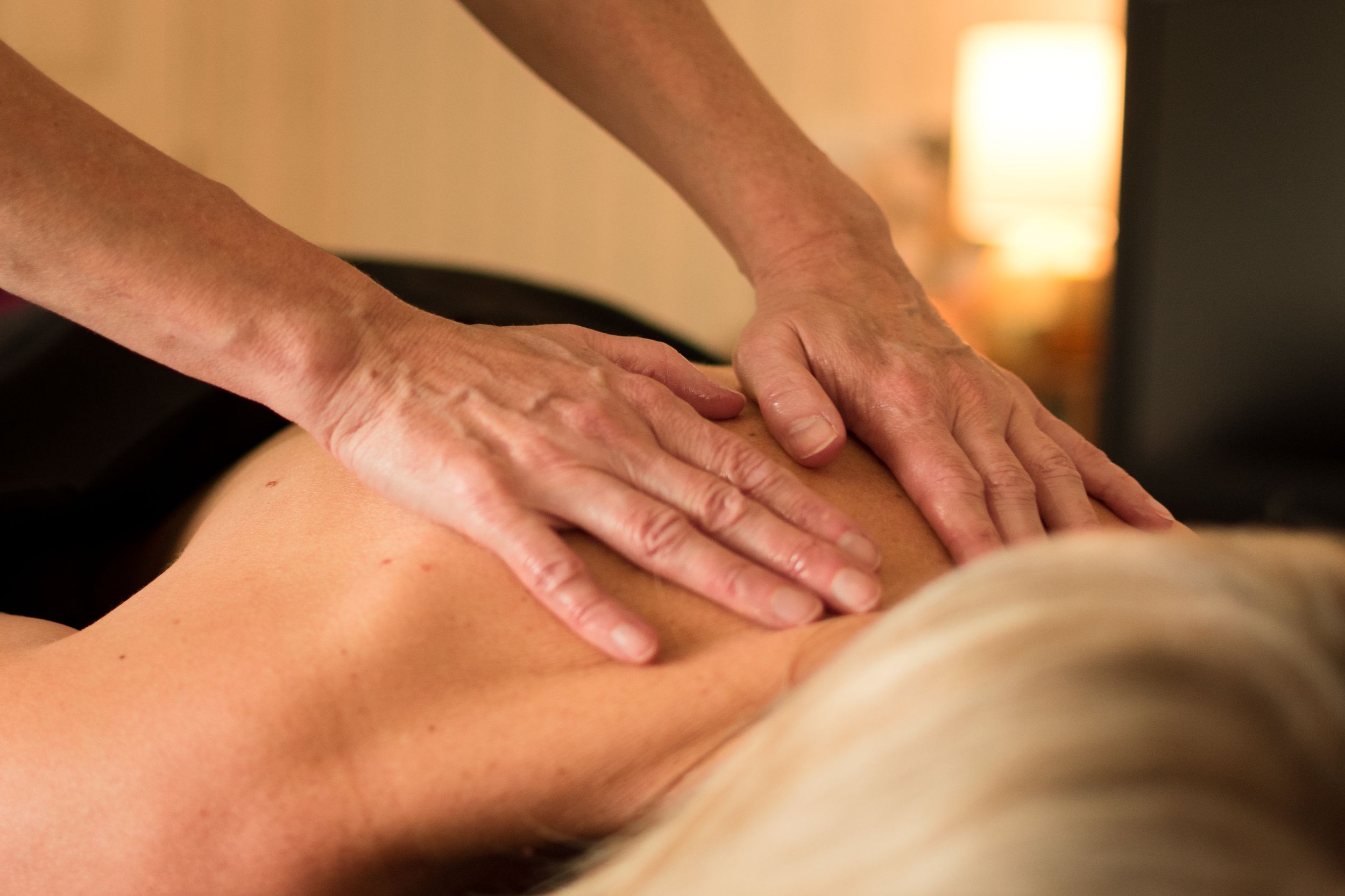 Close up action photo of massage therapist massaging on her clients back.