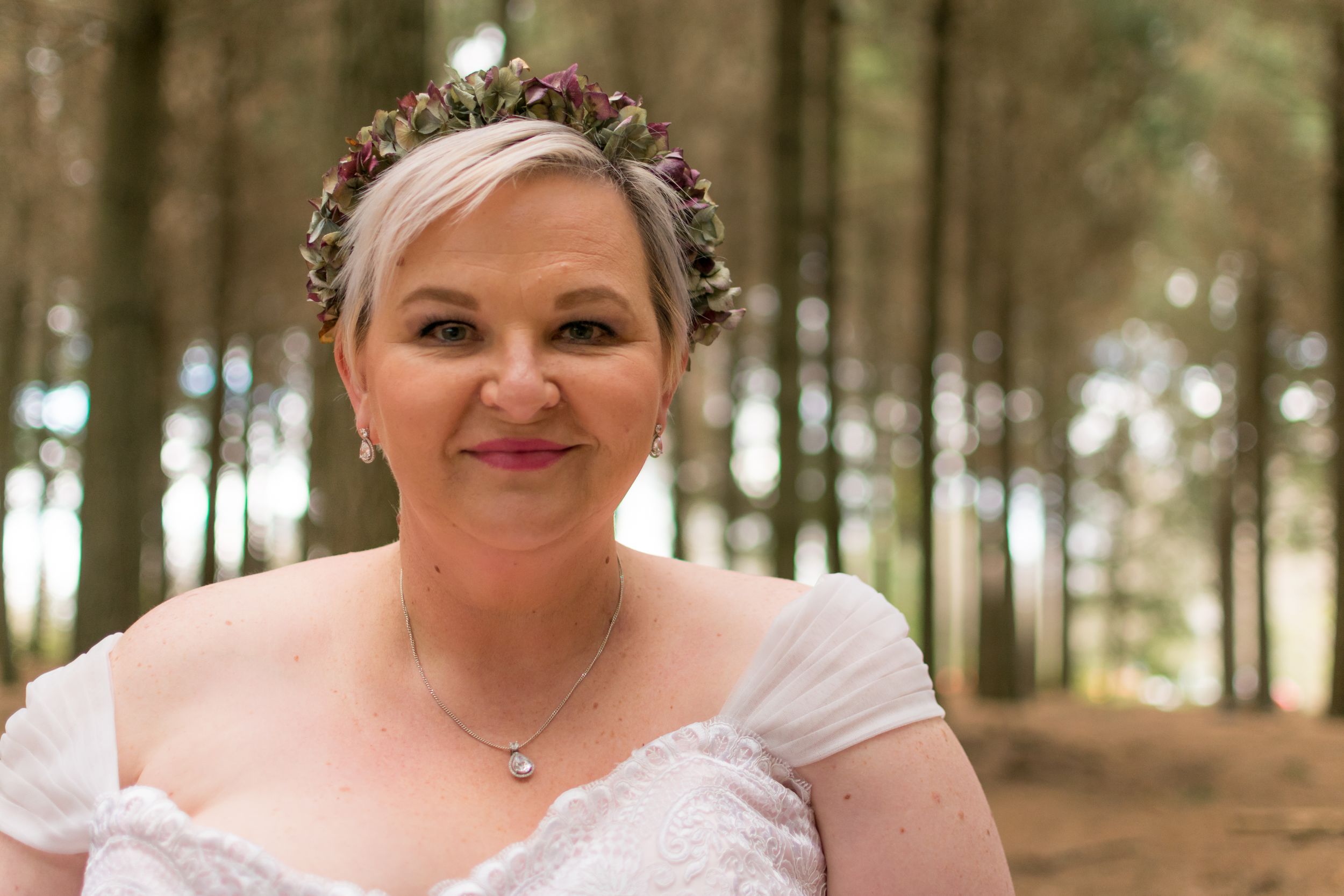 Portrait of bride standing in a forest in Christchurch and looking at the camera and wearing a dried flower crown
