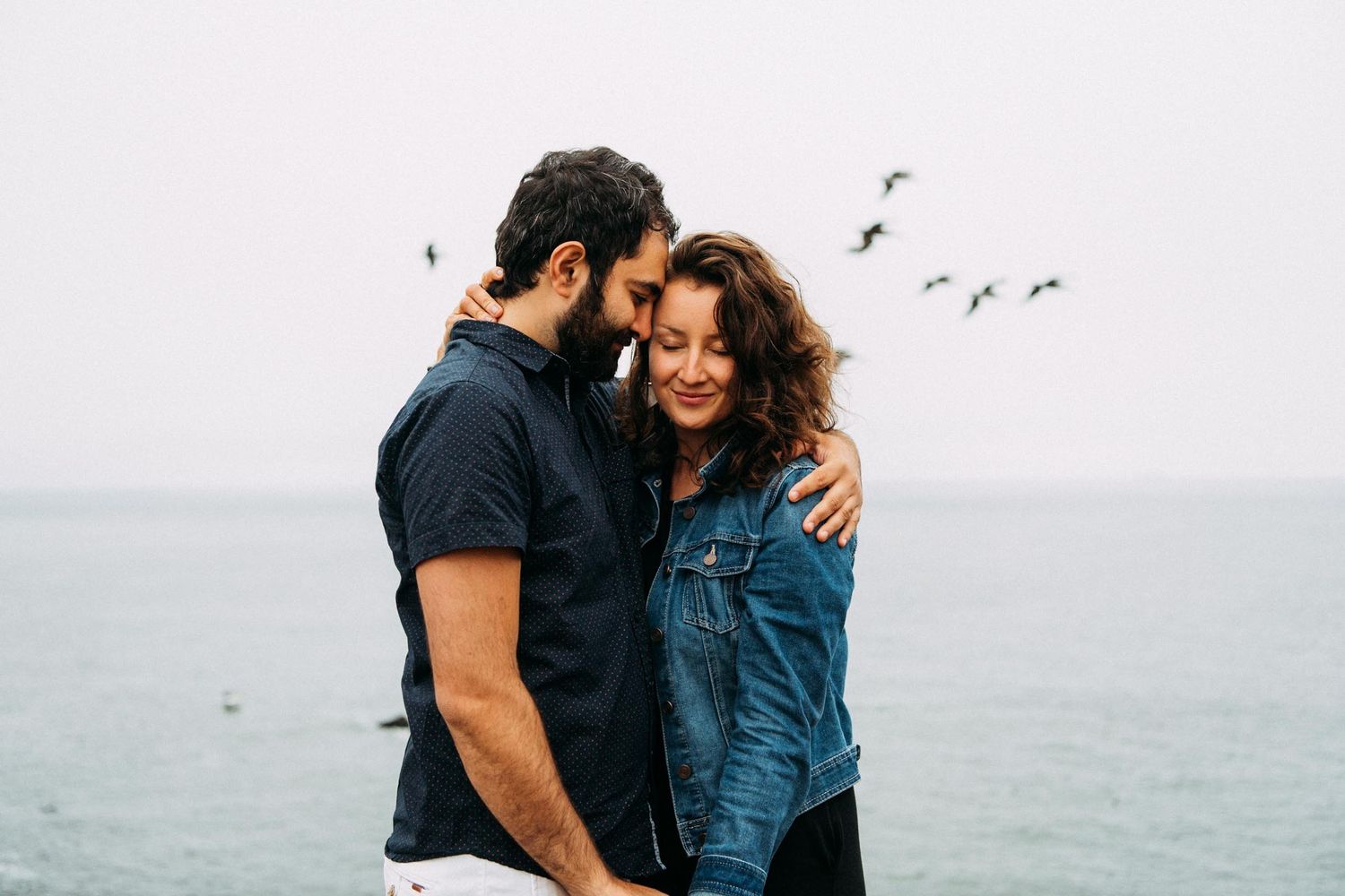 Couple holds each other at Marin Headlands north of San Francisco for engagement portraits.