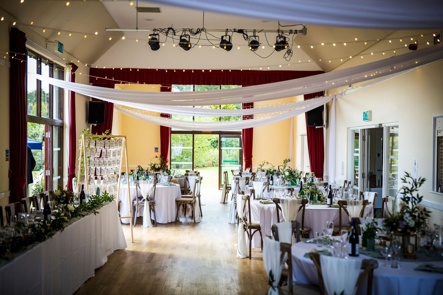 Wedding reception hall decorated with string lights and white drapes creating an elegant atmosphere.