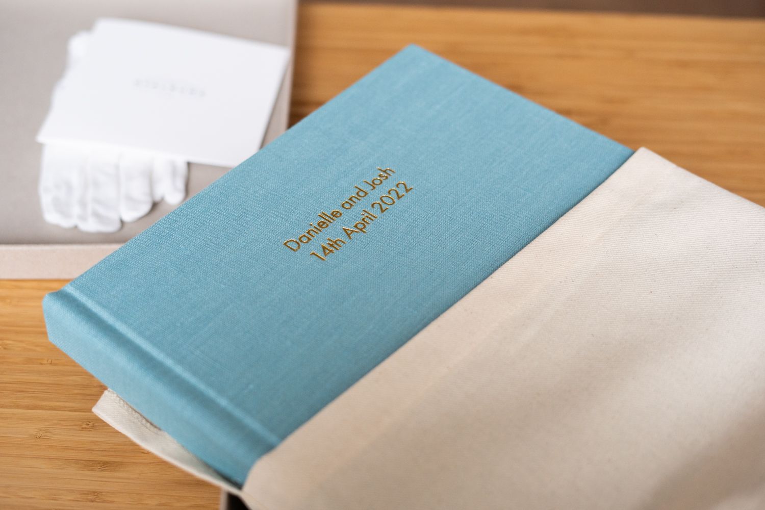 Light blue wedding album with gold text on wooden surface.