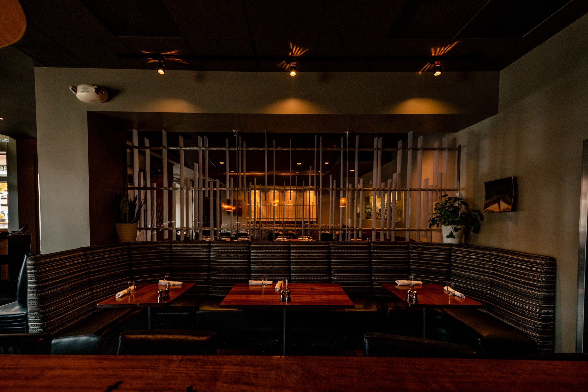 Dimly lit restaurant booth seating with industrial metal dividers and dark ambiance.