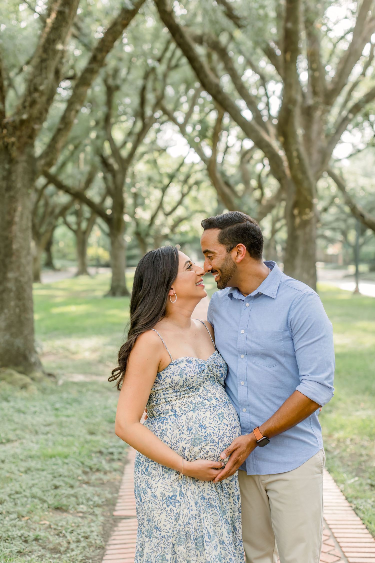 Romantic maternity moment captured under canopy of oak trees.