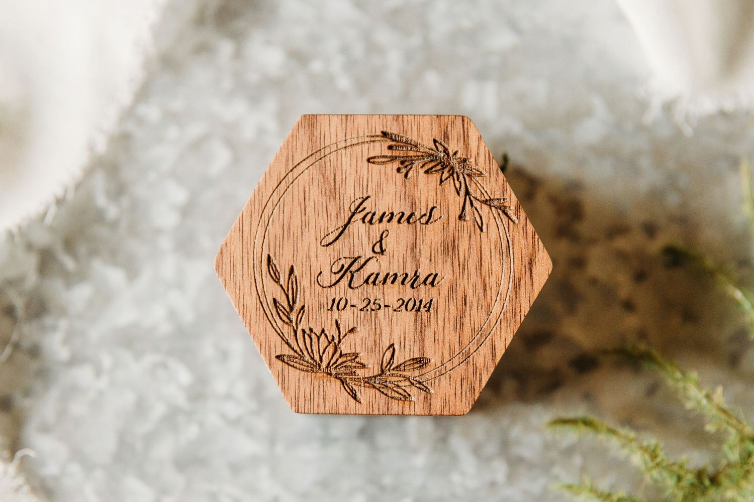 Hexagonal wooden wedding ring box with floral design and names engraved.