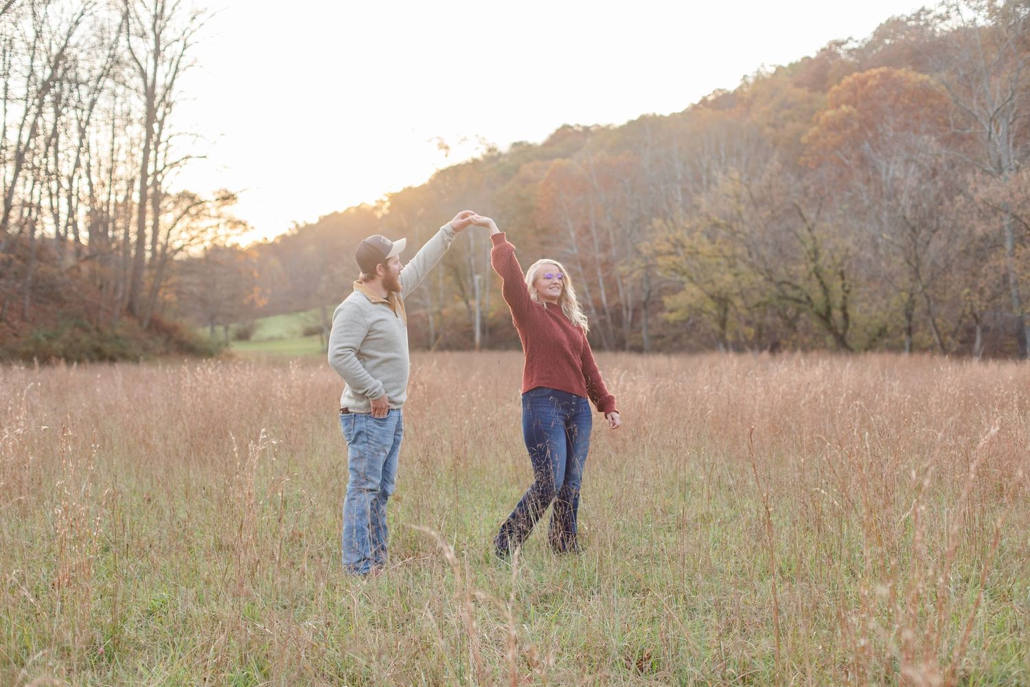 Romantic autumn engagement photo session in a golden grass field at sunset.