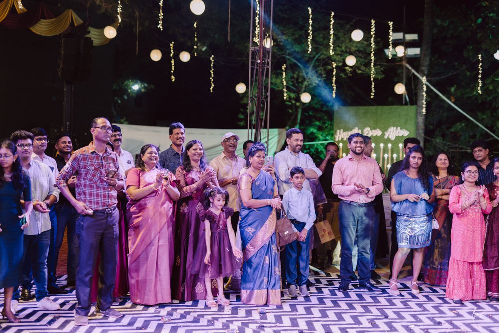 Large group of wedding guests dance in a line formation under purple lighting.