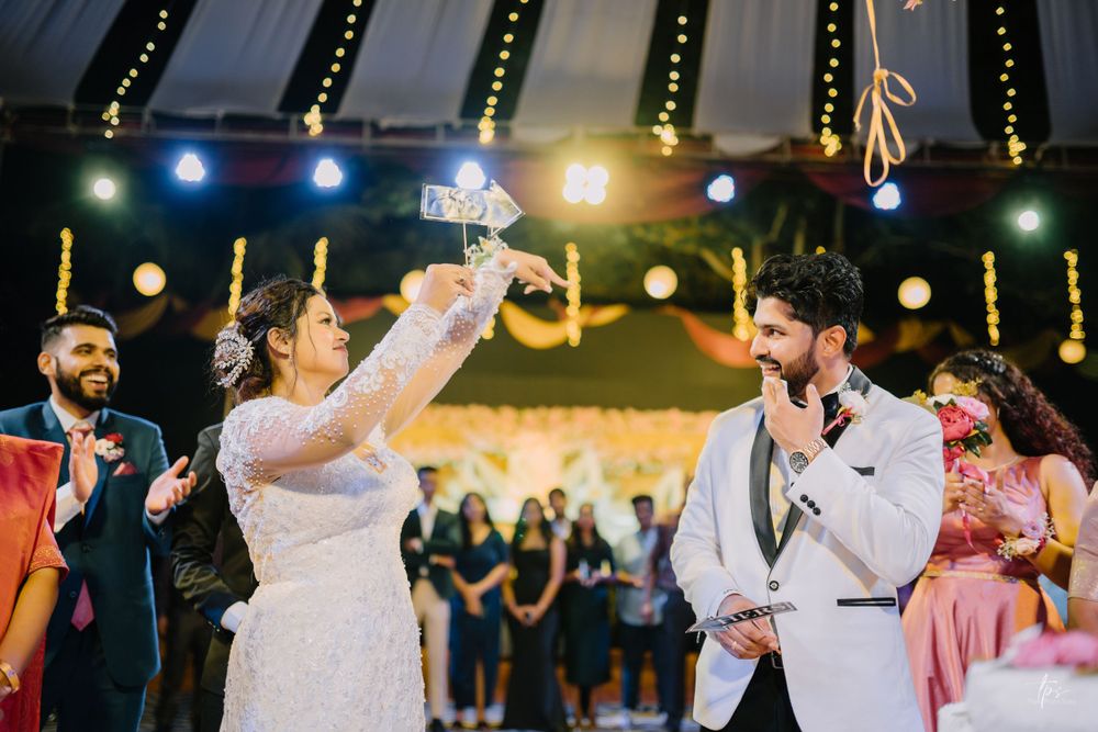 Wedding guests dance and celebrate during evening reception under decorative lighting.
