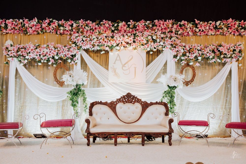 Elegant wedding stage backdrop decorated with pink floral arrangements and white draping.