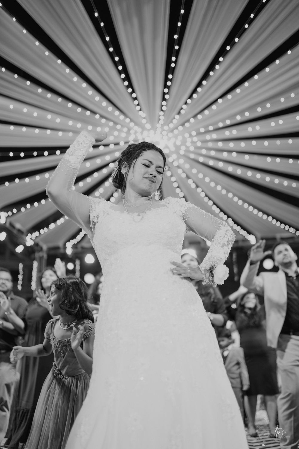 Dramatic black and white photo of wedding reception with starburst lighting pattern overhead.