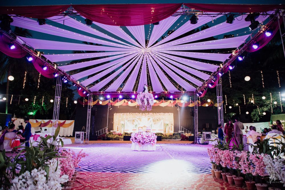 Modern wedding reception venue with dramatic pink and purple lighting and sunburst ceiling design.
