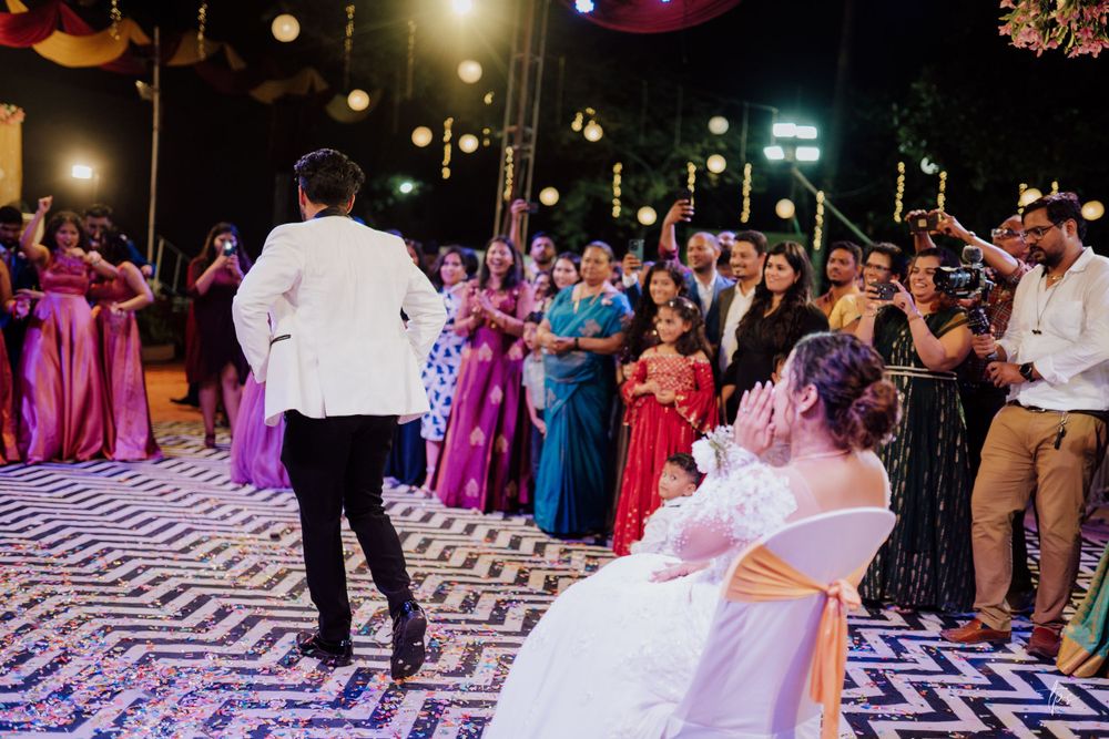 Wedding party celebrates on geometric patterned dance floor under string lights.