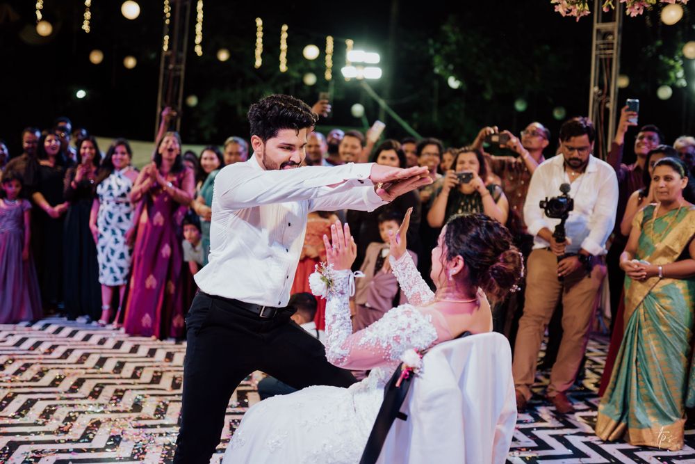 Wedding celebration with guests surrounding illuminated dance floor under tent lighting.