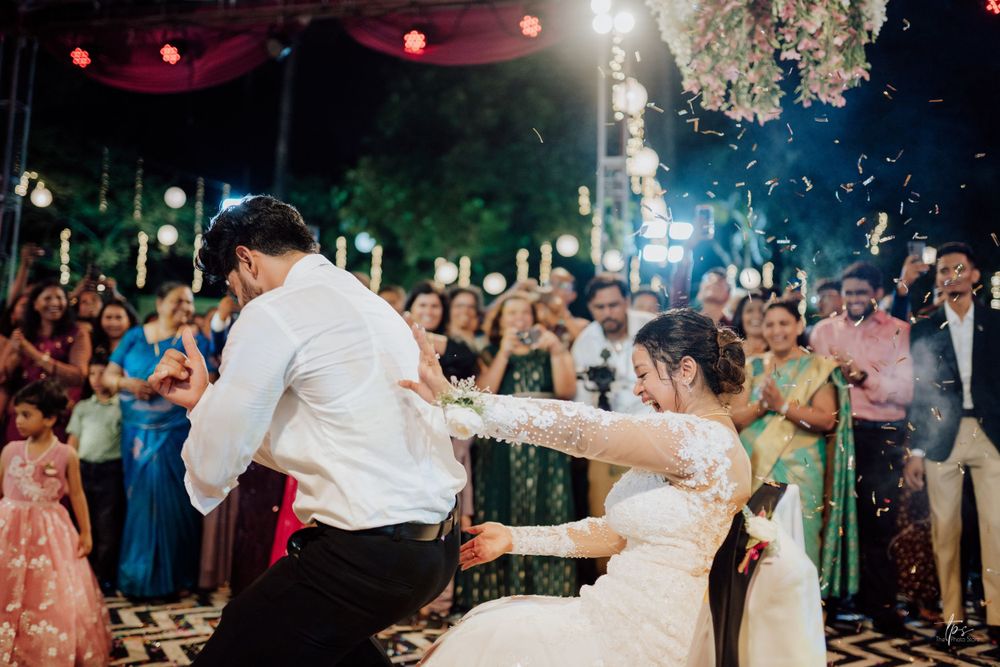 A couple shares their first dance at an outdoor evening wedding reception surrounded by guests.