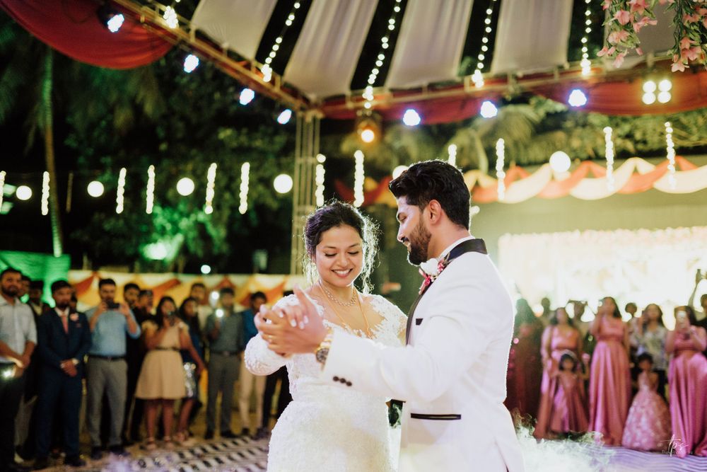 Newlyweds share an elegant dance under string lights at their evening reception.