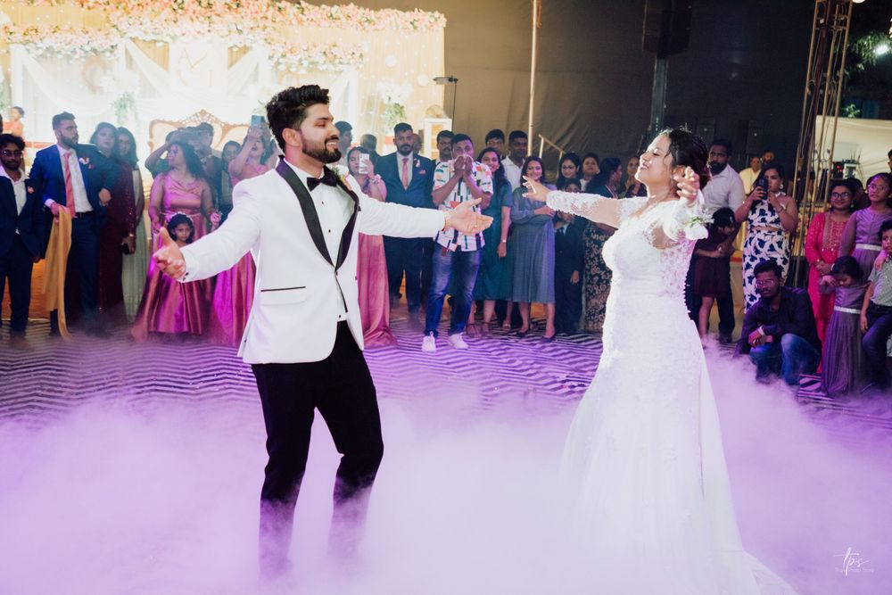 A joyful wedding dance performance on a purple-lit dance floor surrounded by guests.