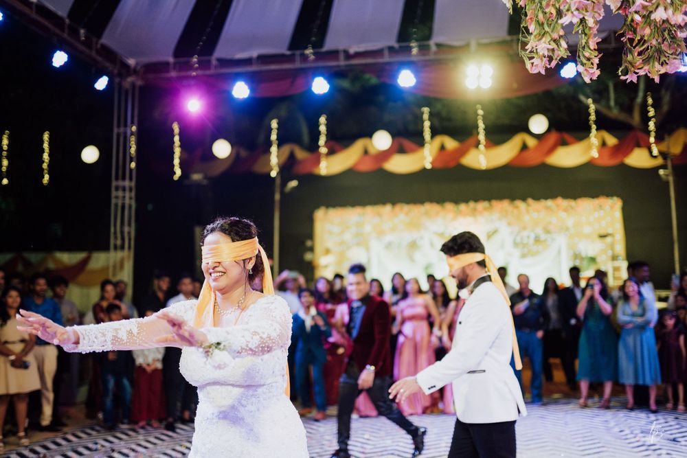 Wedding reception venue decorated with hanging lights and floral arrangements above a patterned dance floor.