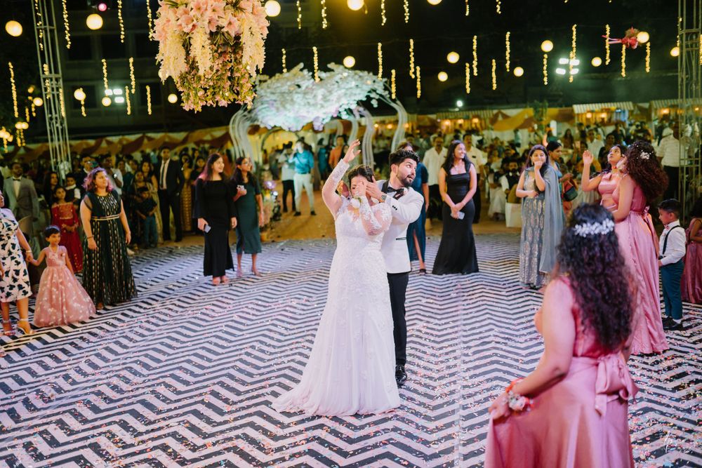 Wedding celebration with guests dancing under twinkling lights and floral arrangements.