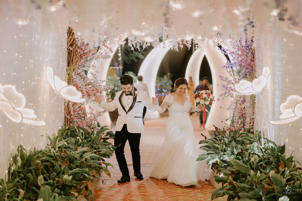 Wedding venue decorated with illuminated butterfly designs and greenery arrangements.