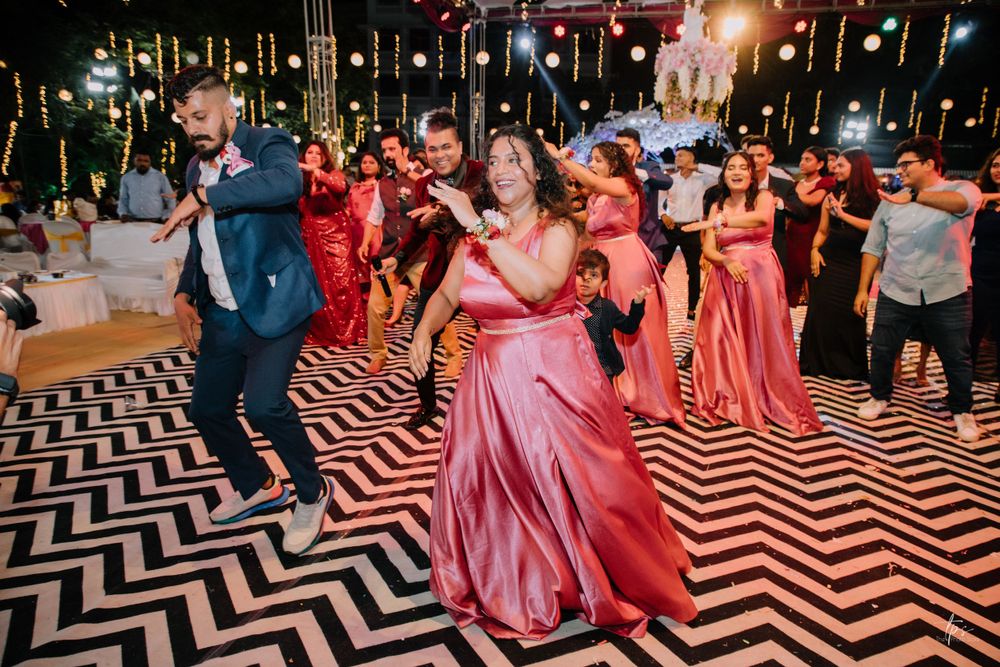 Wedding guests dancing on a geometric patterned floor illuminated by colorful party lights.