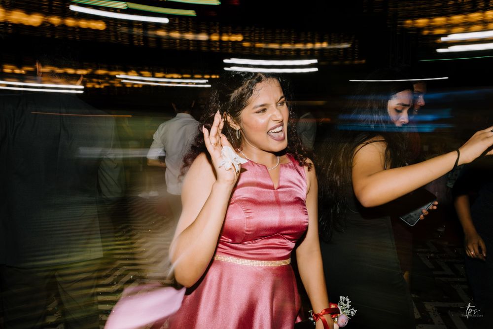 A person in a pink dress dances enthusiastically at a dimly lit party venue with motion blur effects.