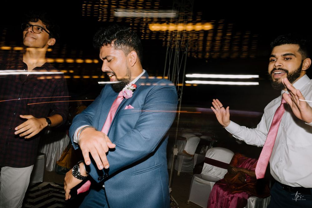 Three people dancing and having fun at a wedding reception with blurred lighting effects.