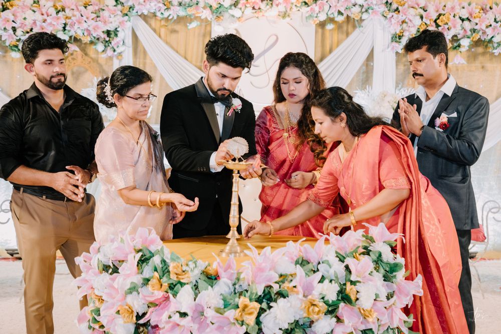 Wedding party gathered around a decorated table performing a ceremonial ritual with flowers and candles.