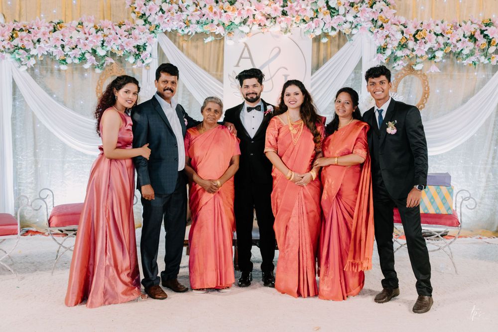Formal group portrait of wedding party members in coordinated coral and black attire.