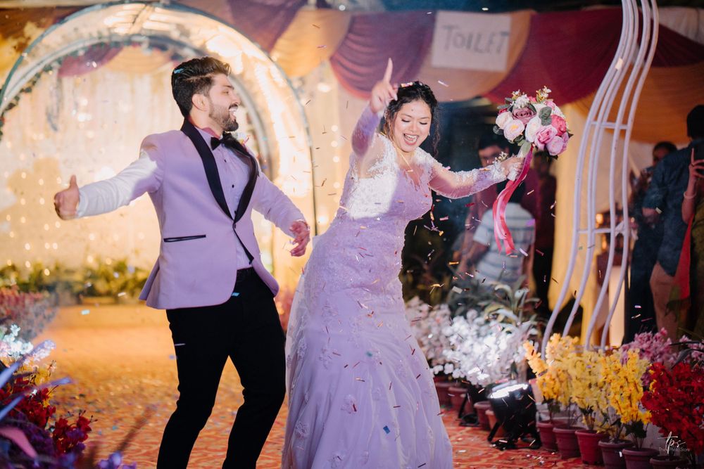 Wedding celebration with couple dancing joyfully under decorated archway.