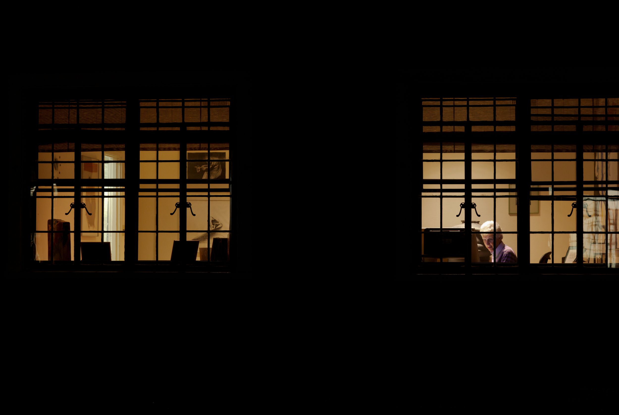 Silhouettes visible through illuminated windows at night on campus building.