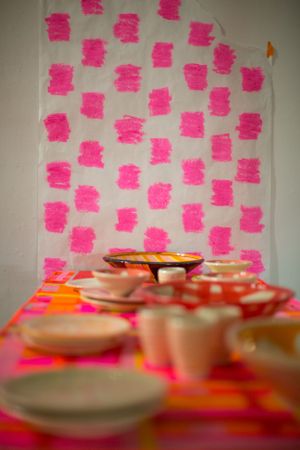 Pink post-it notes arranged in a grid pattern above empty plates on a table.