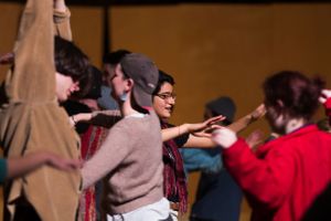 Group of performers engaged in an energetic dance movement on stage.