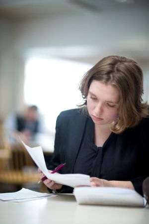 Student reviews academic materials while studying at desk.