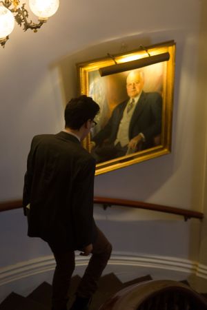A dark hallway with illuminated portrait frames mounted on the wall.