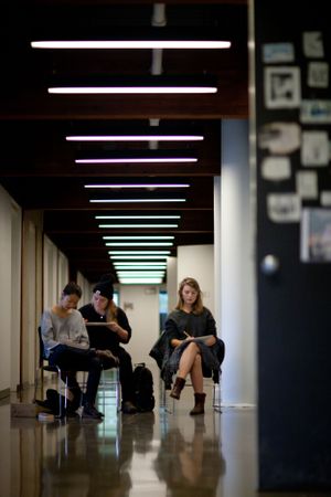 Students study in modern hallway with colorful fluorescent lighting.