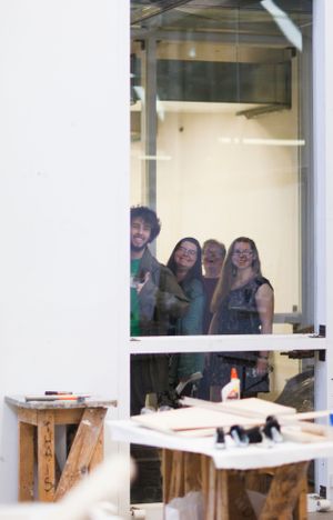 Students smiling and laughing together while looking through a large window.