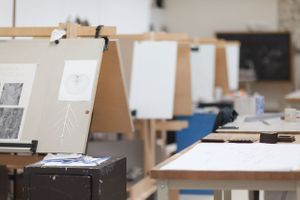 Row of art displays on easels in studio classroom with papers and materials.