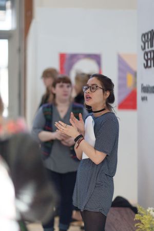 People performing expressive gestures in a bright indoor space with colorful artwork.