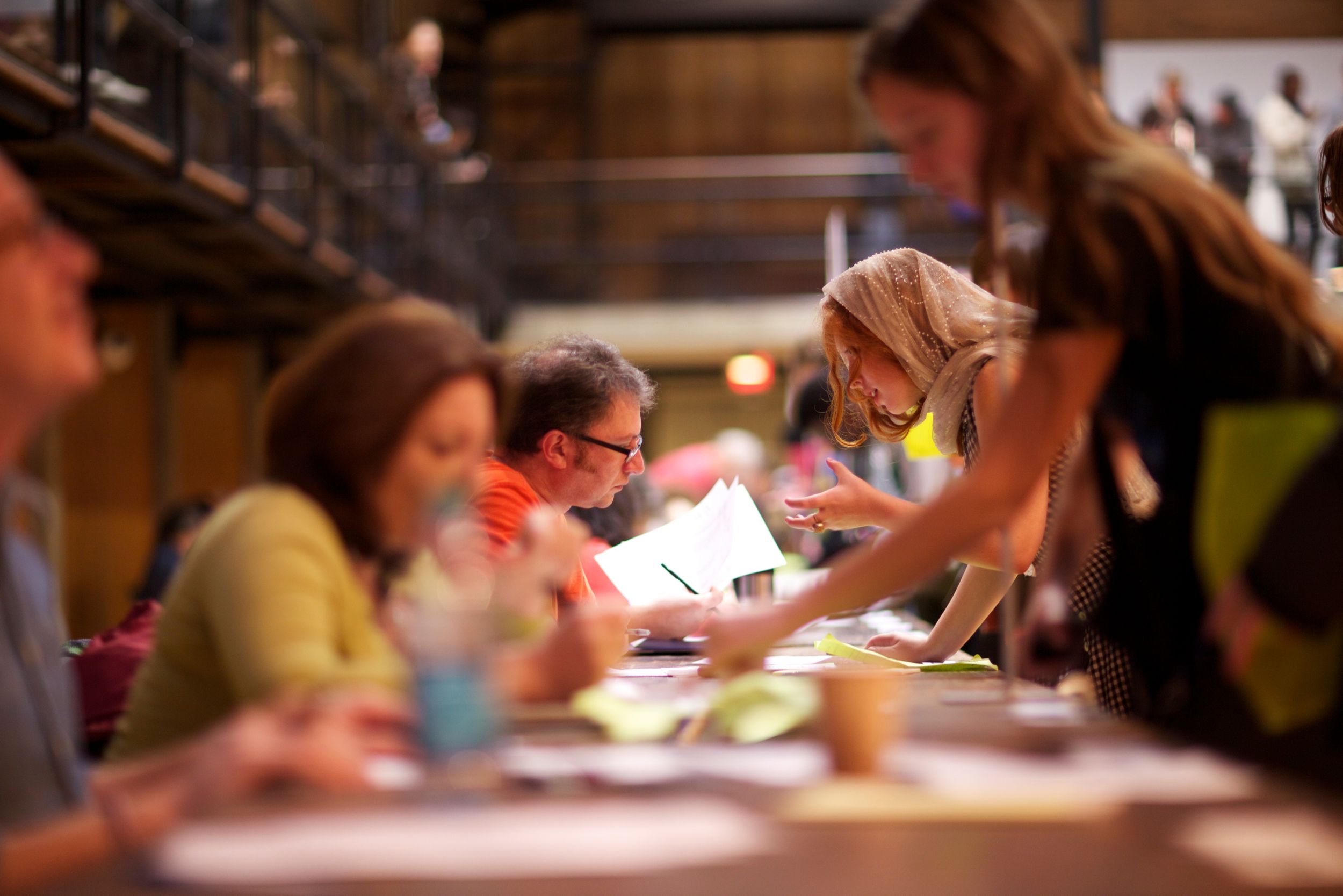 Students working together at a study table in a dimly lit library setting.